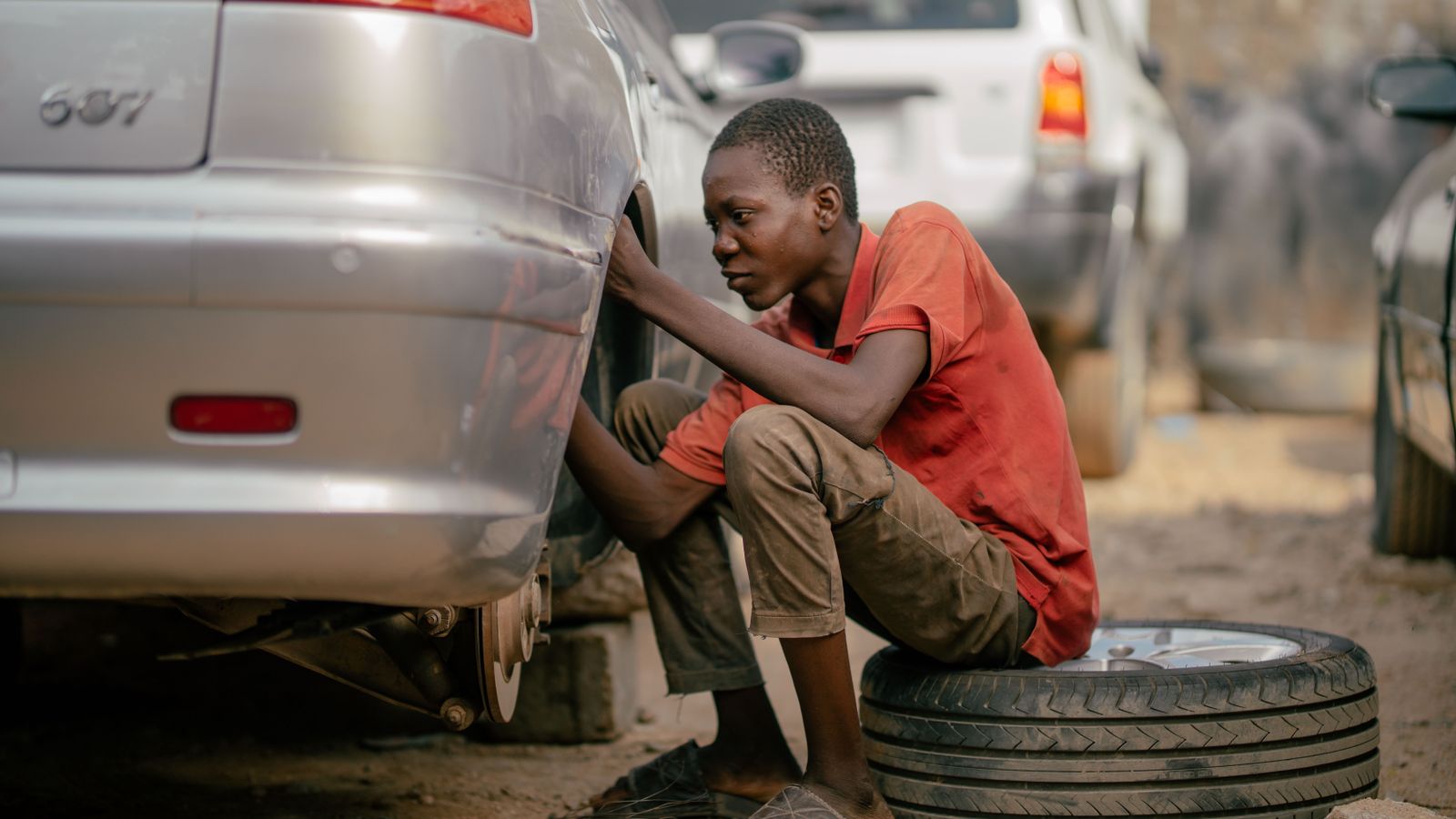 Mechanic working carefully beside a car outdoors