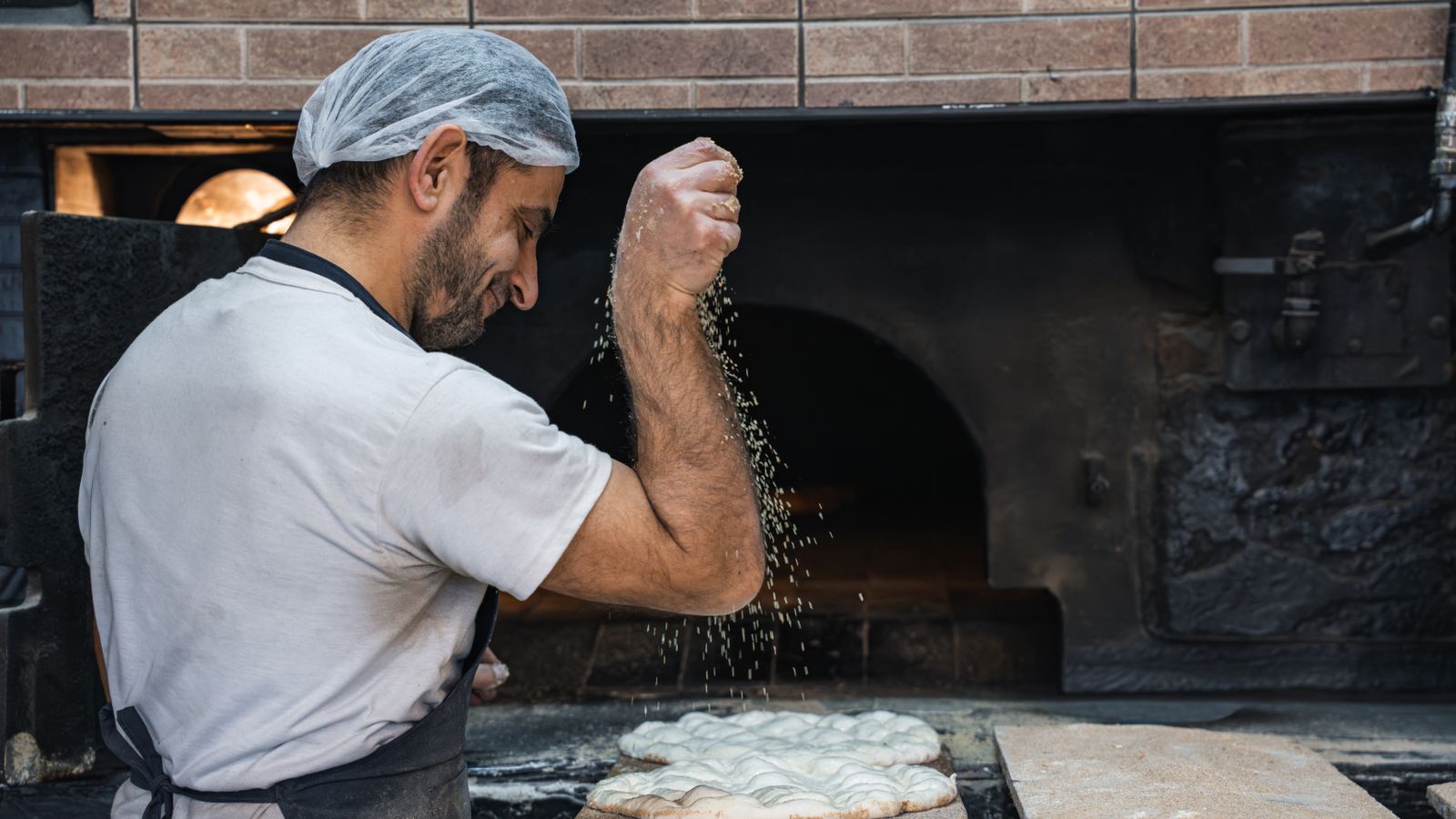 Baker dusting fresh dough with flour before baking
