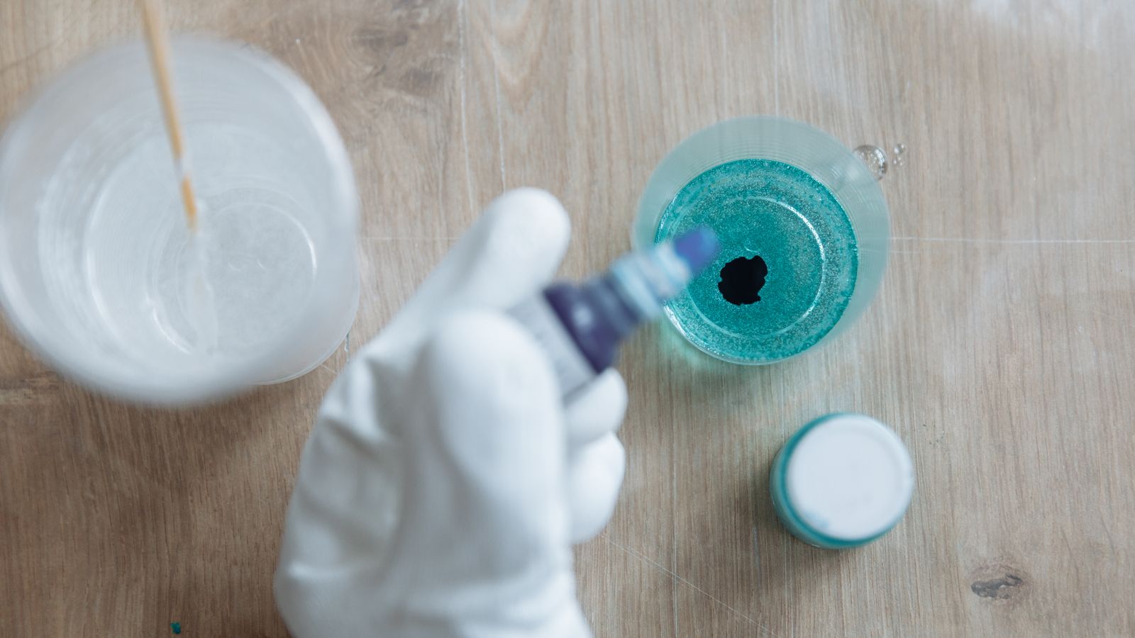 Colored ink being carefully poured into clear craft resin
