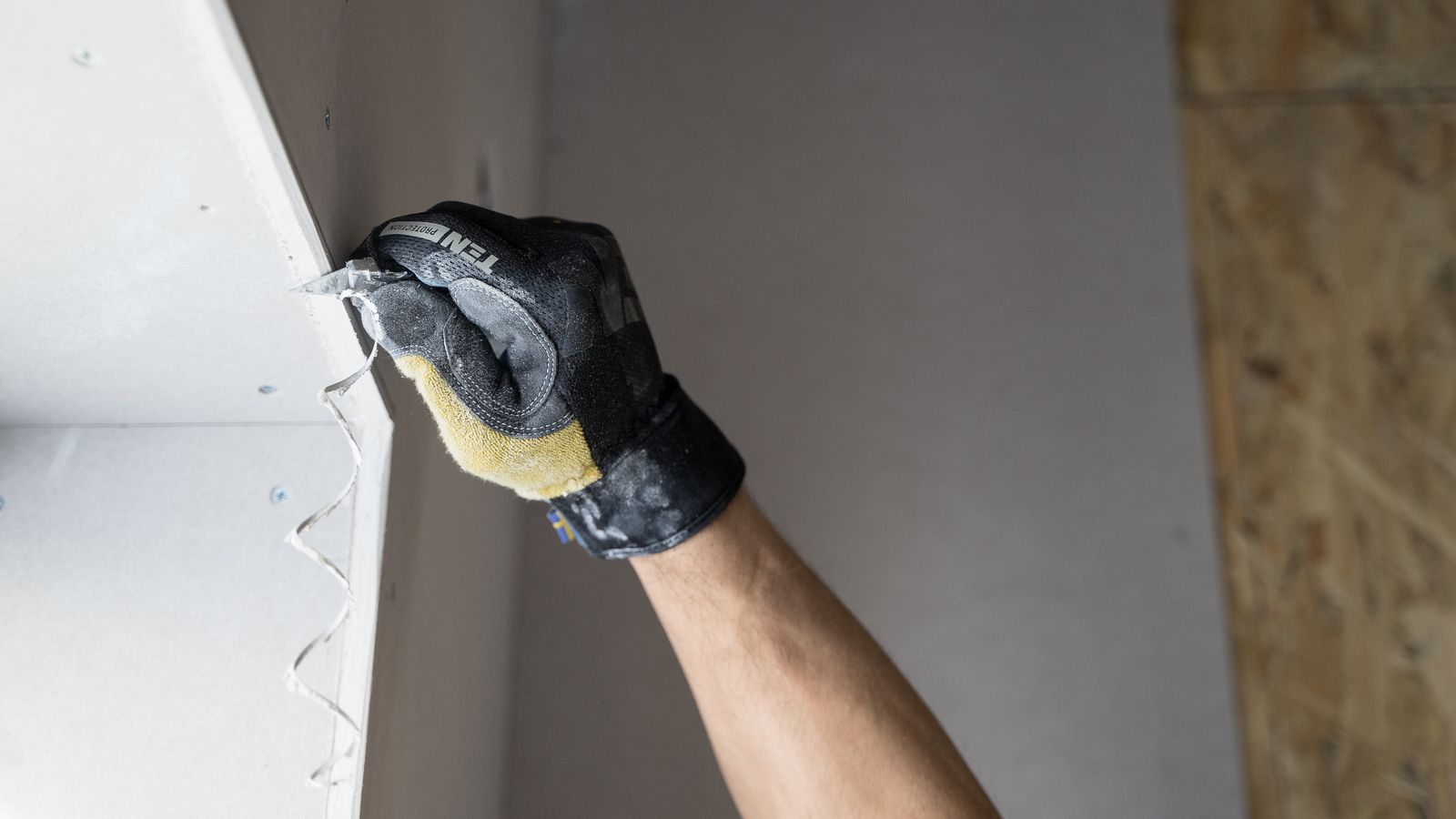 Gloved hand applying plaster smoothly to an interior wall