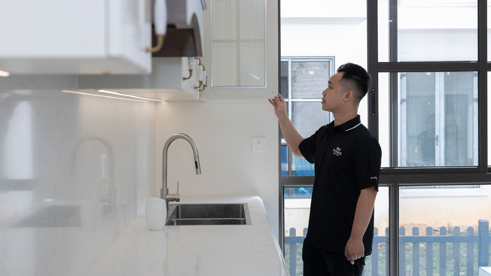 Person inspecting cabinetry and plumbing below a kitchen counter