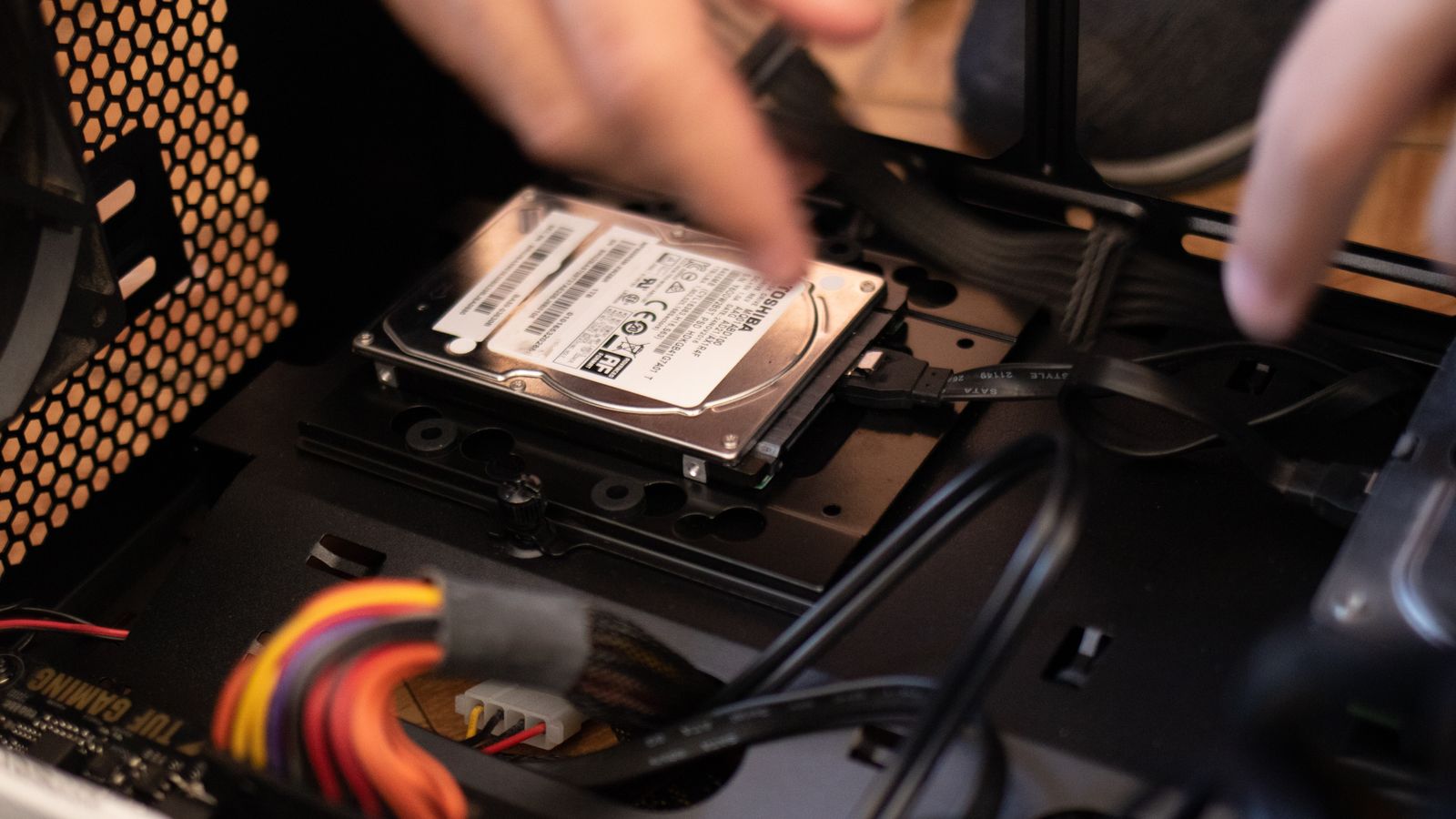 Hands installing a storage drive in a desktop computer